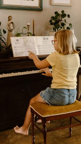 Young girl working in a piano book, practicing piano at home.